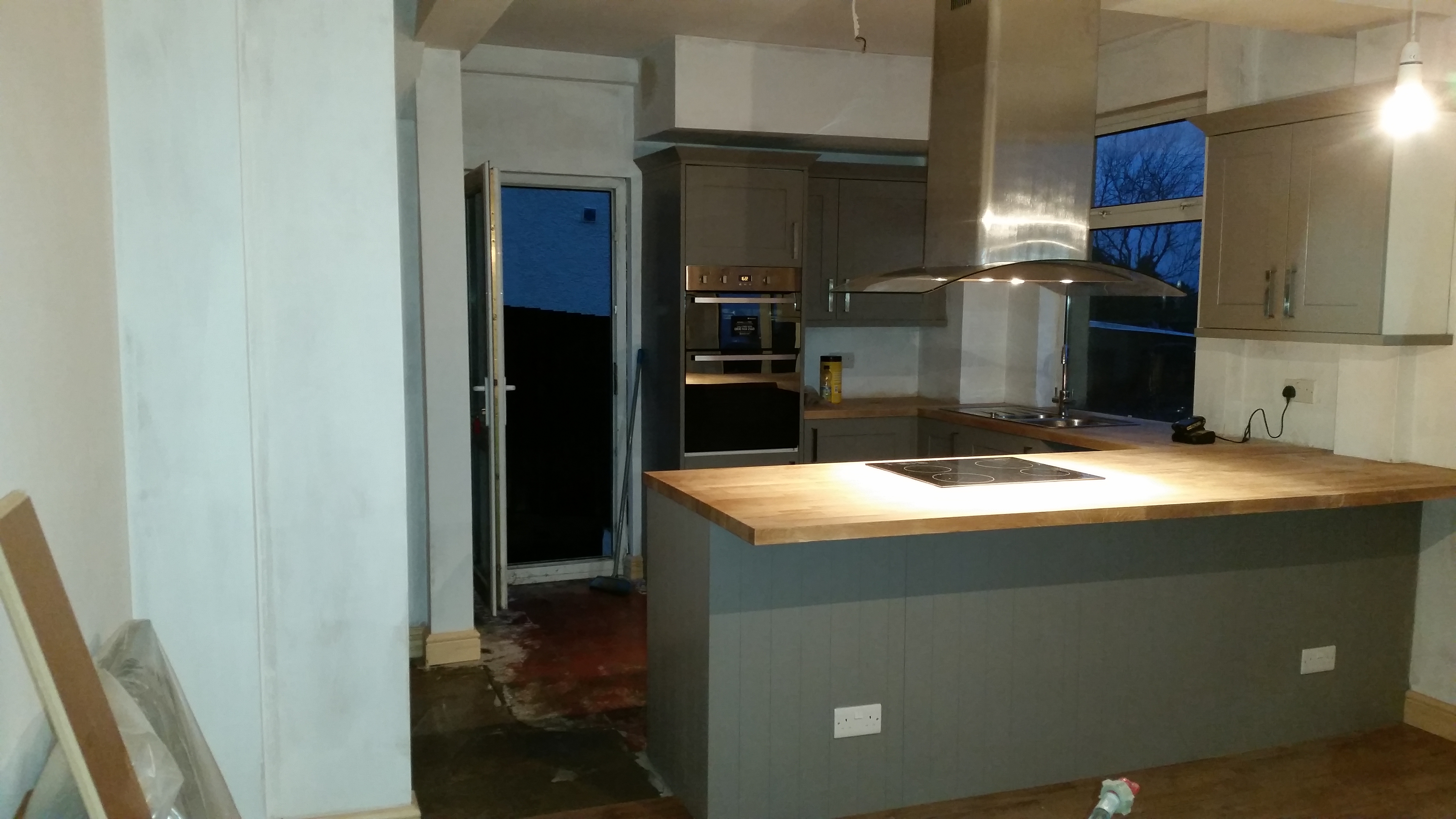 Grey kitchen with a central island, timber worktop and built-in oven