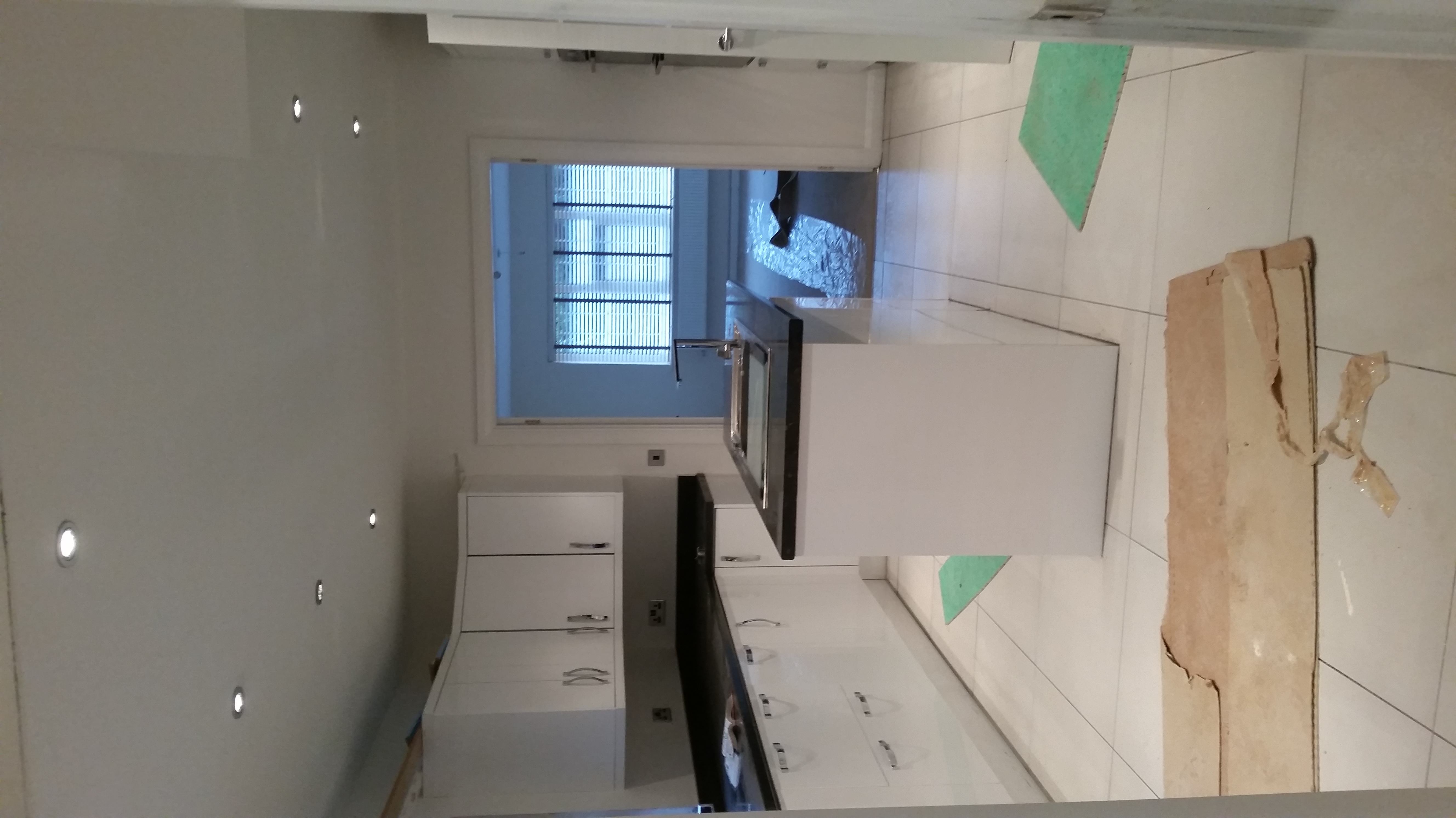 White kitchen cabinetry and a central island, with protective materials on the floor