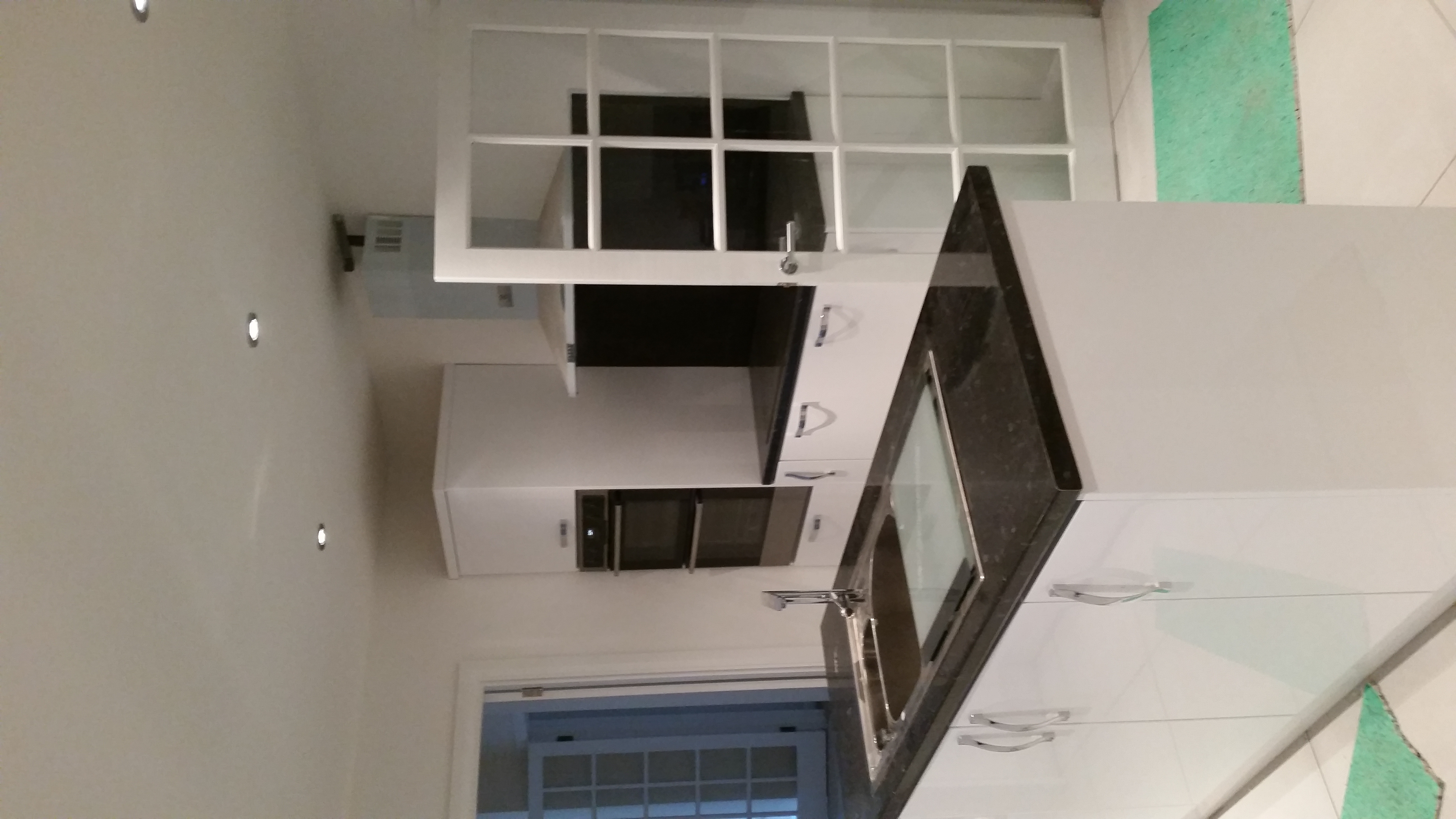 White kitchen with dark worktops, a central island and a built-in oven