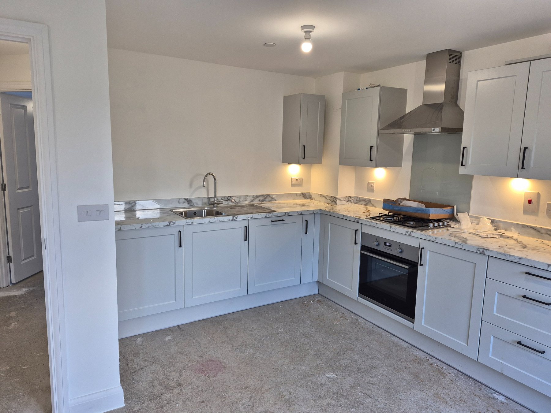 Light grey kitchen cabinetry during installation, with fitting work in progress